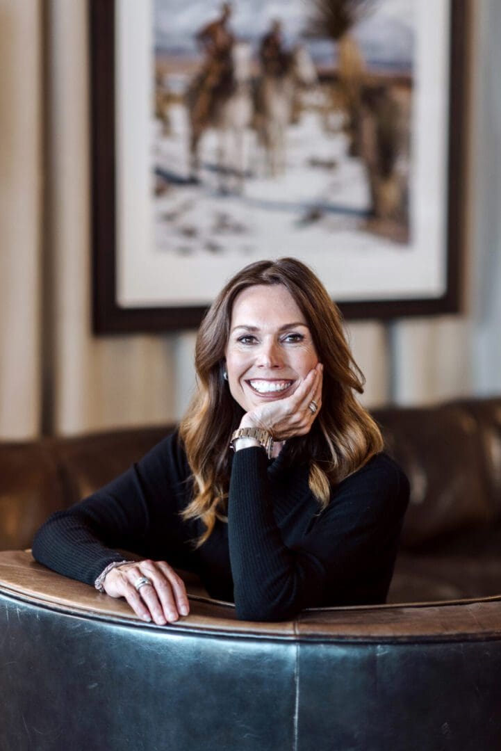 Smiling woman in black sweater sitting at a table indoors.